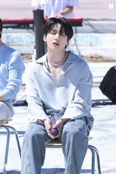 a young man sitting on top of a metal chair next to another person with an apple in his hand