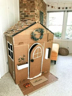 a cardboard house made to look like it has a wreath on top