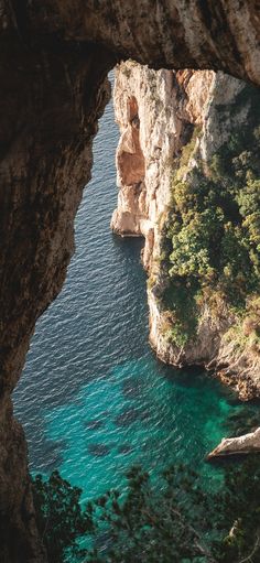 the water is crystal blue and there are cliffs in the distance with trees on either side