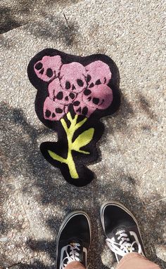 a pair of shoes standing next to a rug with skulls and a tree on it