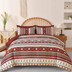 a bed with a red and white comforter on top of it next to a wooden headboard