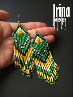 a pair of green, yellow and white beaded earrings in the shape of a bird