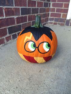 a pumpkin with glasses painted on it sitting in front of a brick wall