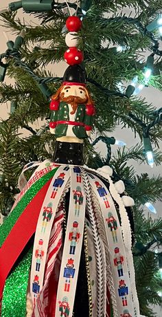 a nutcracker ornament on top of a christmas tree decorated with ribbons