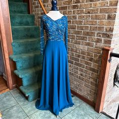 a blue dress is on display in front of a brick wall with stairs behind it