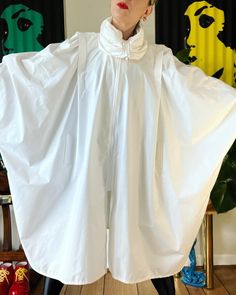 "WINGS. Incredible Vintage 1980's bright white cotton blend batwing jacket with stunning convertible gathered collar and a wingspan to float along your day in. The total package for seasonal layering. Fits a range of sizes (I'm about a M) Up to 40\" bust (on the half) 41\" length Unlined 47/27/26 poly/cotton/nylon Center front zipper closure Gathered convertible high neck Pleated shoulder with gathering Light shoulder pads (can be removed) Curved hem Batwing sleeve with single cuff button closur White Long Sleeve Cape For Spring, White Long Sleeve Spring Cape, Oversized White Cape Outerwear, Fashion Design Sketchbook, Girls Jacket, Batwing Sleeve, Bat Wings, Eminem, High Collar