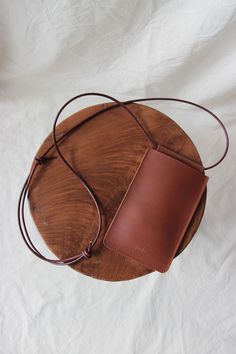 a brown leather purse sitting on top of a wooden table next to a white sheet