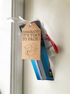 a pair of scissors hanging from the side of a wall next to a card that says congratulations it's time to pack