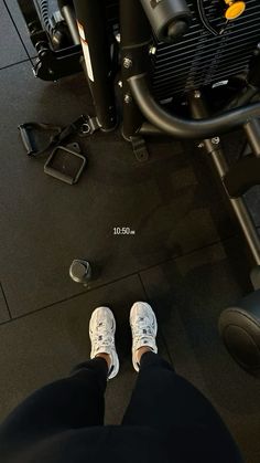 the feet of a person who is standing in front of a gym machine and exercise equipment