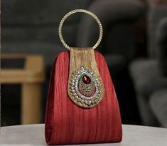 a red purse sitting on top of a white table next to a wooden ring holder