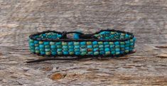 Measures: 9" Can be adjusted down to about 7" Width: 5/8" Weight: 10 grams Want a unique accessory to brighten your day? This Turquoise bracelet is handcrafted with delicate beadwork that has been strung together with leather into an array of blue shades to create a design that will be sure to flatter the wrist. This is an item that will certainly be cherished and appreciated by anyone who treasures handcrafted jewelry! Adjustable Blue Artisan Leather Bracelet, Adjustable Turquoise Wrap Bracelet For Festival, Adjustable Artisan Blue Leather Bracelet, Adjustable Beaded Turquoise Leather Bracelet, Adjustable Turquoise Beaded Leather Bracelet, Adjustable Turquoise Hand-strung Wrap Bracelet, Adjustable Turquoise Hand-strung Beaded Bracelets, Turquoise Adjustable Hand Wrapped Friendship Bracelets, Adjustable Hand Wrapped Turquoise Friendship Bracelets