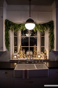 a kitchen decorated for christmas with evergreen garland and pine cones on the window sill