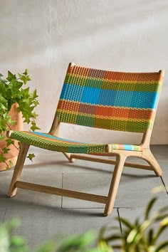 a wooden chair sitting next to a potted plant on top of a tile floor