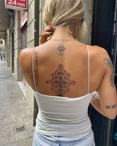 a woman with tattoos on her back standing in front of a building