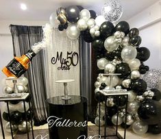 balloons and decorations are on display at a 50th birthday party in black, white and silver