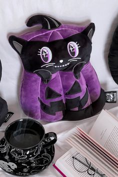 a black and purple cat stuffed animal next to an open book