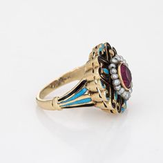 This is part of Chairish’s Fine Jewelry assortment.  Elegant and finely detailed Edwardian era enamel ring (circa 1900s to 1910s), crafted in 14 karat yellow gold.    Created ruby measures 5mm (in very good condition and free of cracks or crisps). Small natural 1mm seed pearls surround the ruby.   A created ruby is set into a beautifully detailed scrolled mount. Blue and black enamel adds a pop of colour, offering contrast to the ruby that is striking and unique. The ring is small in size (2 1/2 Victorian Enamel Ring For Anniversary, Yellow Gold Enamel Jewelry With Rose Cut Diamonds, Victorian Enamel Wedding Ring, Victorian Yellow Gold Ruby Ring With Intricate Design, Victorian Style Hallmarked Enamel Ring For Anniversary, Victorian Yellow Gold Enamel Ring For Anniversary, Antique Enamel Rings For Formal Occasions, Antique Yellow Gold Enamel Ring, Victorian Ruby Ring In Yellow Gold With Intricate Design