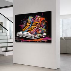 a pair of sneakers with colorful graffiti on the upper part of them are hanging in a white room