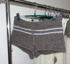 two pairs of shorts hanging on a clothes rack next to some sweaters and socks