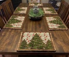 a wooden table topped with place mats covered in green and red flowers on top of it