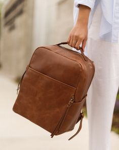 The go-anywhere bag, our La Jolie is the perfect backpack for the on-the-go parent, gym goer, jetsetter and more. With a capacity you wouldn't imagine, this bag can truly carry you through the day. Featuring limitless interior and exterior pockets for space as well as our finest luxe leather, look no further for the perfect bag. Our Luxe leather is more reactive to the touch and will feel lived-in over time. Hand selected because of its vintage feel and character, this full grain leather breaks Leather Diaper Bag Backpack, Leather Diaper Bag, Beautiful Backpacks, Stroller Hooks, Work Backpack, Backpack Free, Vegan Leather Bag, Diaper Bag Backpack, Feel Pretty