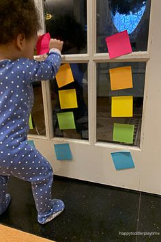 a toddler playing with post it notes on the front door