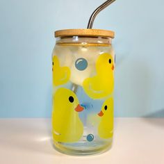 a glass jar with yellow rubber ducks on it and a straw sticking out of the lid