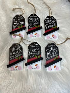 four christmas tags with snowmen on them sitting on a white furnishing area