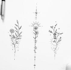 three flower tattoos on the side of a white paper with pen and ink next to it