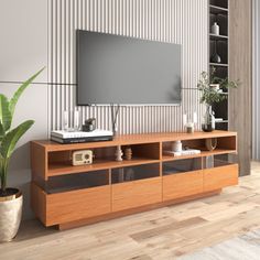 a living room with a large television on top of a wooden entertainment center next to a potted plant