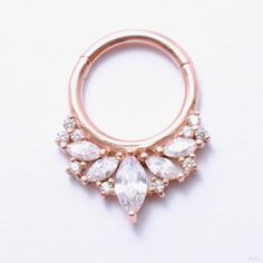 Like an ornate crown for your piercing, this solid gold hinged ring is a burst of sparkling gemstones. Marquise-cut stones of varying sizes are clustered together in a unique arrangement and accented by ten 1mm matching stones, all prong-set to allow for maximum brilliance. Elegant Diamond Septum Ring With Accents, Elegant Cubic Zirconia Septum Ring With Diamond Accents, Cubic Zirconia Cluster Jewelry With Halo, Halo Cluster Jewelry In Cubic Zirconia, Gold Cluster Jewelry With Sparkling Stones, Rose Gold Round Jeweled Jewelry, Rose Gold Jeweled Round Jewelry, Elegant Halo Hoop Septum Ring, Elegant Rose Gold Septum Ring For Wedding