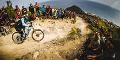 a man riding a bike on top of a dirt hill next to a group of people