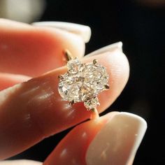 a close up of a person's hand holding a ring with a diamond in it