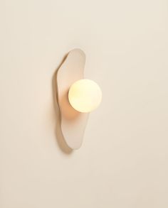 a white wall light mounted on the side of a wall next to a lamp shade