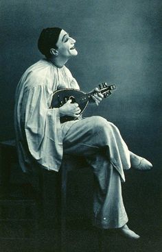 a black and white photo of a man with a guitar in his hand, laughing