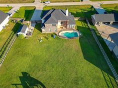 an aerial view of a house with a swimming pool in the yard and lots of grass