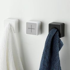 a towel hanging on the wall next to two square knobs and a cross sign