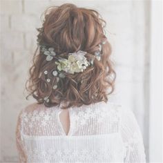 the back of a woman's head wearing a white dress with flowers in her hair