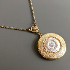 "White Sunflower Locket Necklace - Antiqued Gold and White Plated Sunflower attached to Antiqued Gold and White plated Locket with a pretty floral design.  The locket dangles from an Antiqued Gold plated Flower Connector. The Locket is approximately 30 mm (1.25\") in diameter. Antiqued Gold plated Chain For other sunflower designs:  https://www.etsy.com/shop/mcstoneworks/search?search_query=sunflower&order=date_desc&view_type=gallery&ref=shop_search For other locket designs: http://www.etsy.com/ Adjustable Vintage Flower Shaped Jewelry, Adjustable Flower Charm Necklace For Wedding, Adjustable Wedding Flower Necklace With Charm, Vintage Locket Necklace With Adjustable Chain For Wedding, Adjustable Flower Charm Necklaces For Wedding, Vintage Locket Necklace For Wedding, Adjustable Necklace With Flower Charm For Wedding, White Flower-shaped Jewelry With Sunflower Design, White Flower Jewelry With Sunflower Design