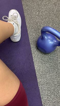 a woman sitting on the ground next to a blue exercise ball and shoelaces