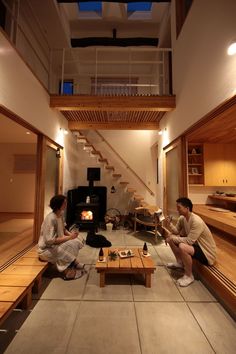 two people sitting on the floor in front of an open fire place with stairs leading up to them