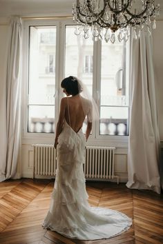 the back of a bride's dress in front of a window with chandelier