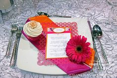 a pink and orange place setting on a white plate