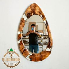 a man taking a selfie in front of a mirror with wood carvings on it