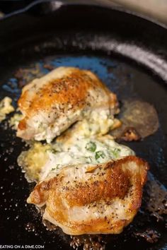 two pieces of chicken cooking in a skillet with cheese and herbs on the side