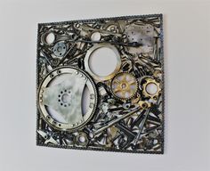 an art piece made out of assorted metal parts on a white wall with one hole in the middle