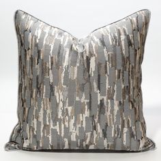 a gray and white pillow with an abstract design on the front, sitting against a white background