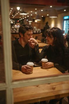 two people sitting at a table with coffee cups