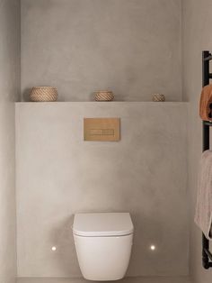 a white toilet sitting in a bathroom next to a towel rack