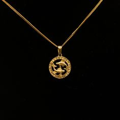 a gold necklace with an image of a horse in the center on a black background